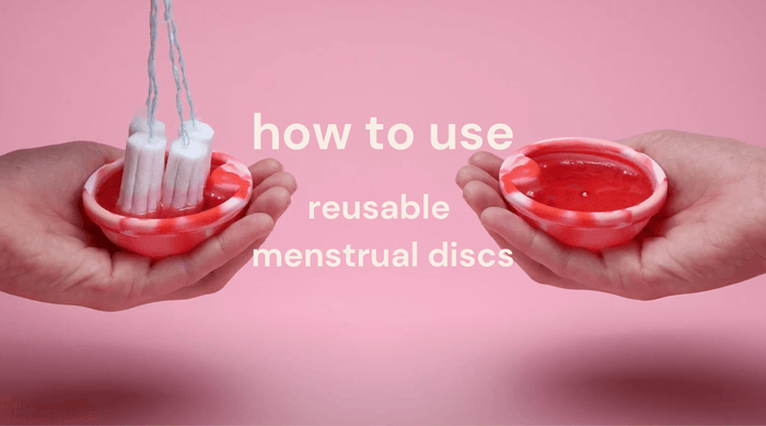 Hands holding Bodyotics reusable menstrual discs with flowing menstrual fluid on pink background and text "how to use reusable menstrual discs"