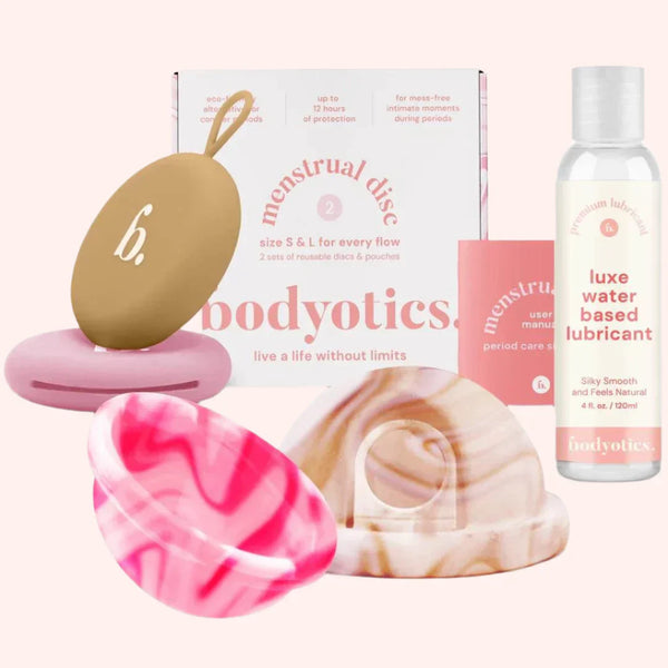 Bodyotics set with water-based lube, beige reusable menstrual discs in two sizes, and pink carry pouch for intimate care and cycle comfort